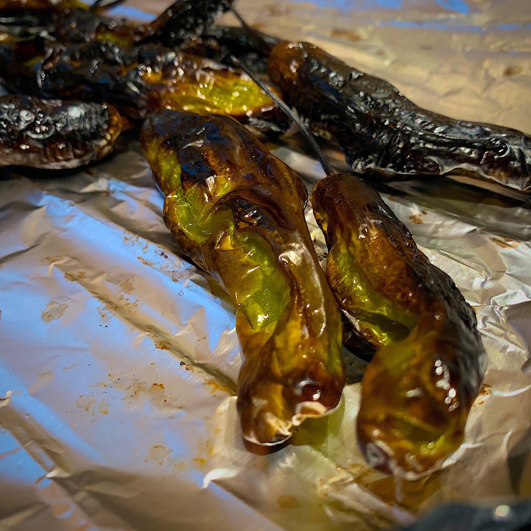 blacked long thin peppers on tin foil