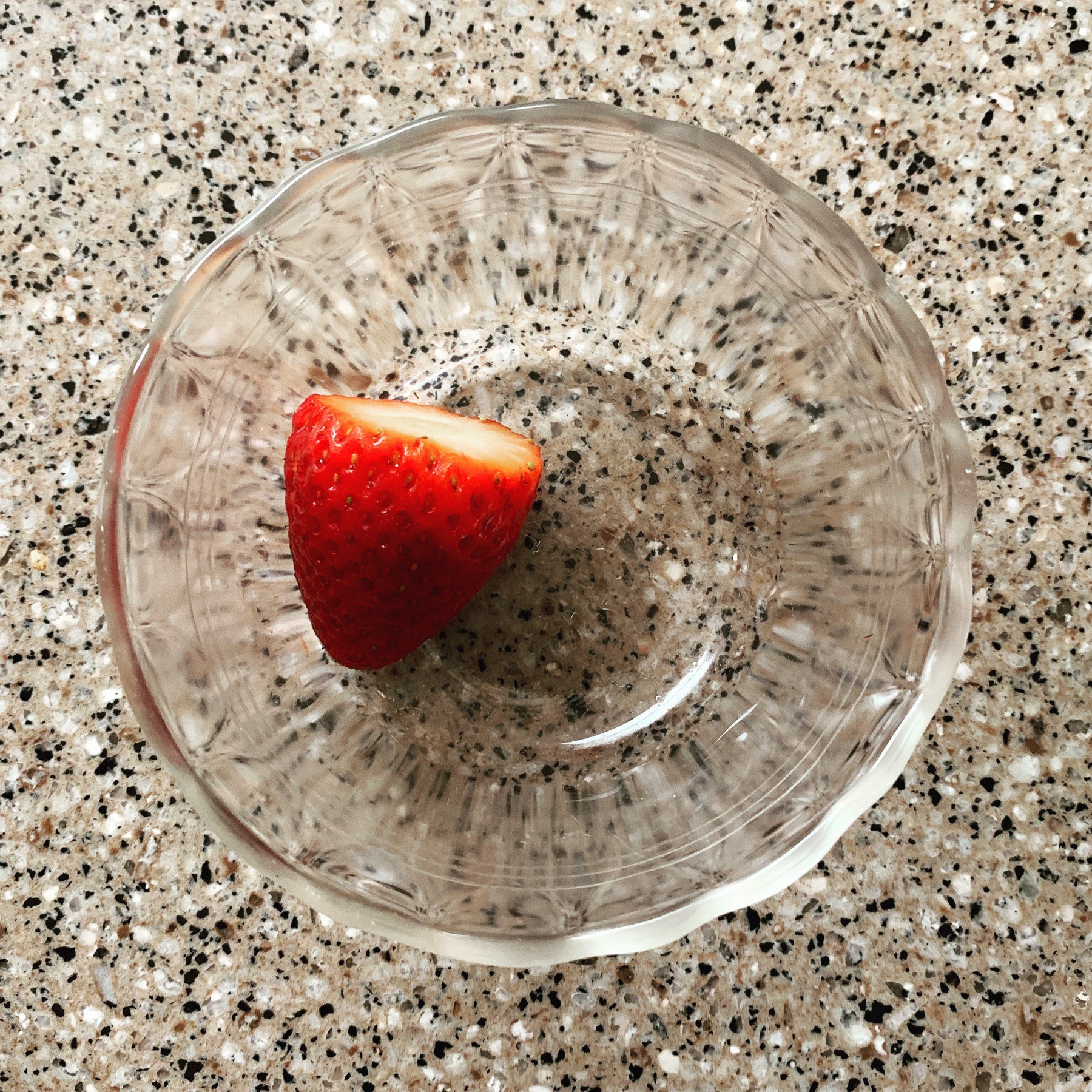 a single strawberry in a glass bowl